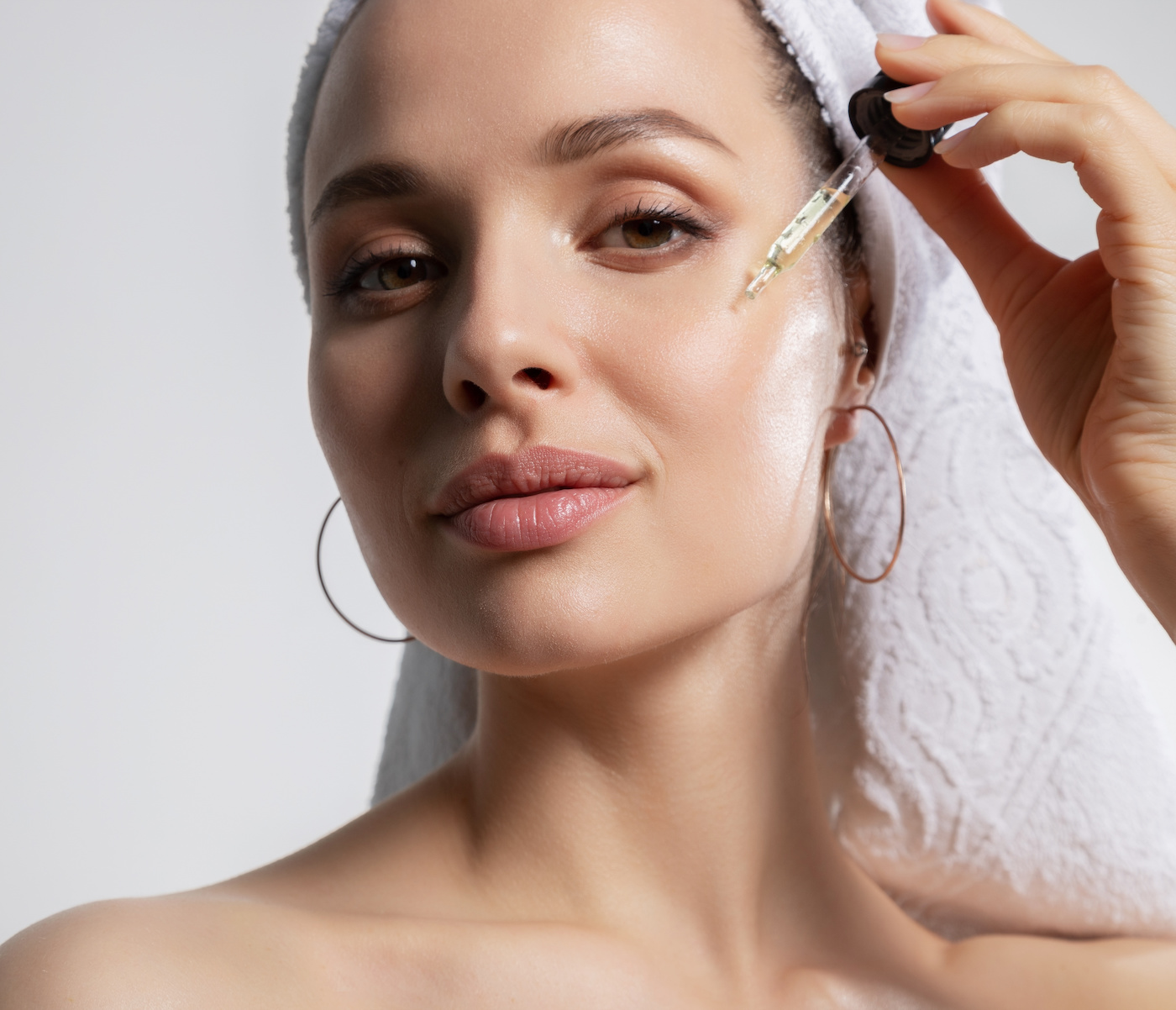 Beautiful woman applying oil serum